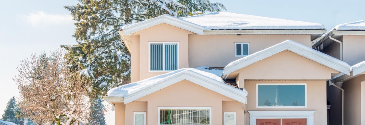 home in late winter with snow on roof and hedge