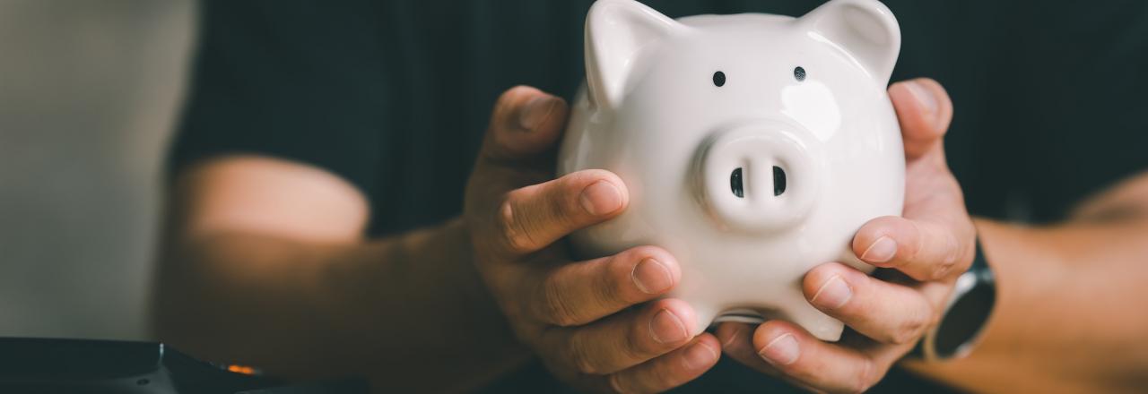 man holding piggy bank with coins below his hands