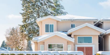 home in late winter with snow on roof and hedge