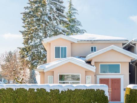 home in late winter with snow on roof and hedge